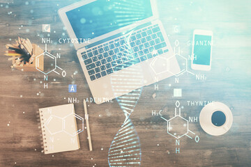 DNA hologram drawings over computer on the desktop background. Top view. Multi exposure. Concept...