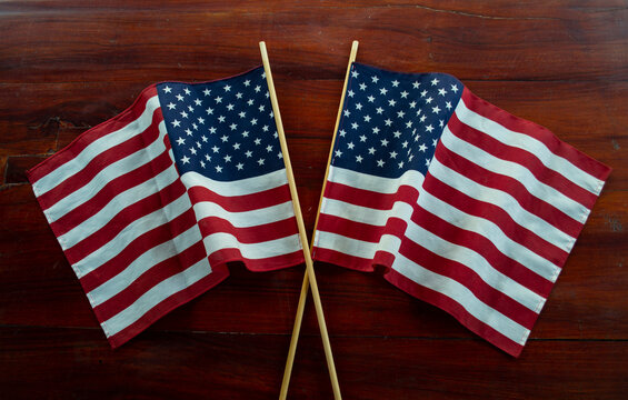 Two US USA American flags crossed on an old wooden vintage rustic table for celebrating memorial and national day of independence 4th 4 fourth July, ideal for a background image 
