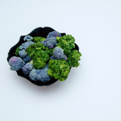 cauliflower lies in a black plate isolated on a white background.