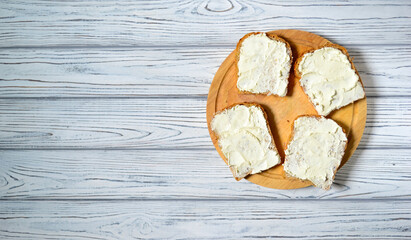 Homemade sandwiches with cream-cheese on a wooden table. Top view. Sandwiches on a white plate