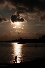 someone walking by the sea at sunset