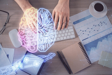 Double exposure of man's hands typing over computer keyboard and brain hologram drawing. Top view....