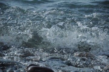 Spray of white sea foam and wet sea pebbles