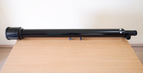 Telescope tube parts with long focal lengths on wooden table. Astronomy lesson exploring parts of...