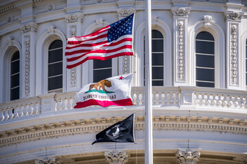 The US flag, the California flag and the POW-MIA flag waving in the wind in front of the Capitol...