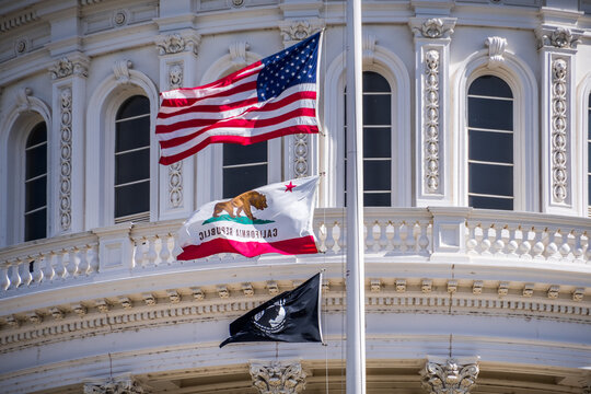 The US flag, the California flag and the POW-MIA flag waving in the wind in front of the Capitol State Building in downtown Sacramento