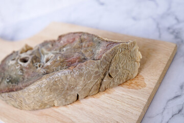 Raw beef lungs close up on a wooden cutting board. Sliced cow lung detail