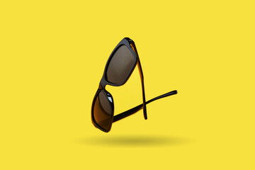  black sunglasses over yellow background. outer space. side view. minimal summer concept