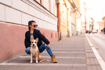 Naklejka na ściany i meble Beautiful caucasian girl with sunglasses squats on the street next to her dog breed American Staffordshire Terrier