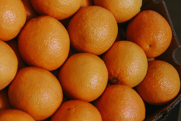 Juicy oranges in a cardboard box on market. Orange wallpaper. Yellow background.