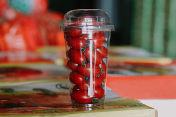 Plastic cup with cherry tomatoes against the background of bazaar.