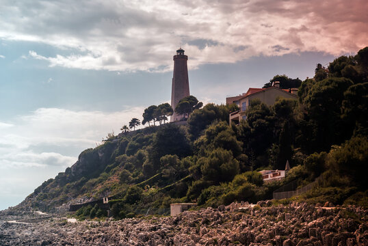 Lighthouse on Hill Covered with Trees and Bushes Shot Through Orange Filter - Buildings on Cape in Front of Summer Blue Sky on Cap Ferrat, Nice, France