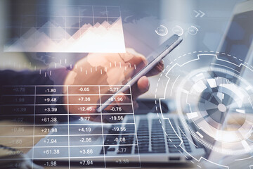 Double exposure of man's hands holding and using a phone and financial graph drawing. Analysis concept.