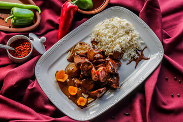 Beef with vegetables in soy sauce with cooked rice. A dish on a red background. A spicy dish of...