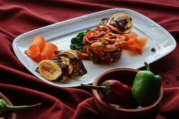 Fried chicken with vegetables. Pepper, broccoli, eggplant, paprika and potatoes. A dish on a red background.