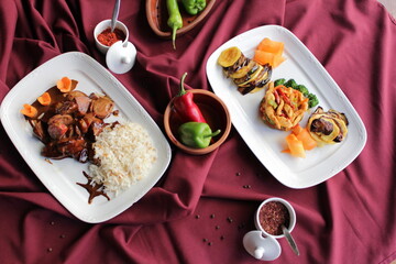Fried chicken with vegetables. Pepper, broccoli, eggplant, paprika and potatoes. A dish on a red background.