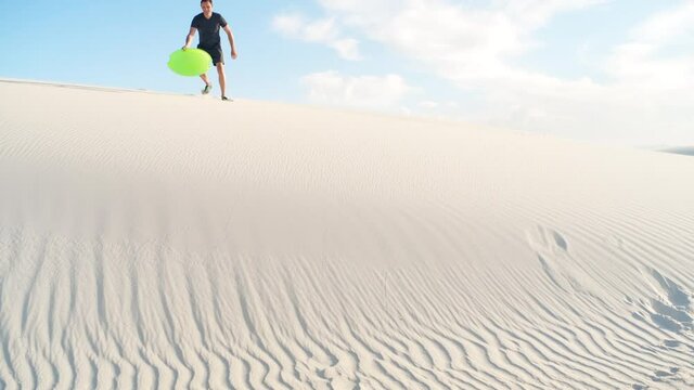 Happy man on sand in white sands dunes national monument in New Mexico on disk sled sliding down hill