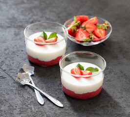 Panna cotta vanilla with strawberries in a glass Cup on a dark gray background