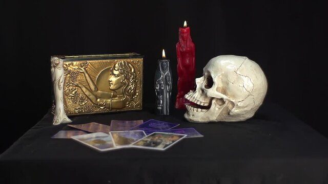 magical beautiful skull with mystical burning candles of black magic and an ancient psychic box, fortune telling and divination on falling tarot cards