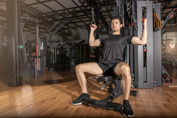 Fototapeta na wymiar Fit man exercising workout with weights machine for arms in the gym