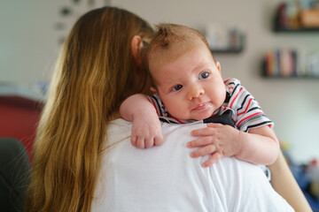 Mother holds her two moths old baby on the shoulder at home - Caucasian woman with her newborn...