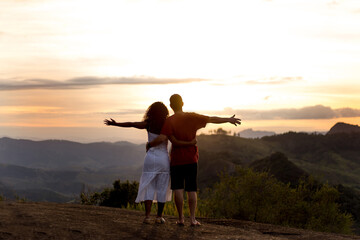 Boyfriends  with arms raised and landscape in the background. Dating couple.