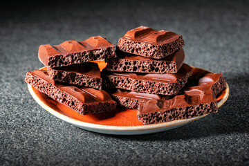 chocolate pieces in plate on gray surface.