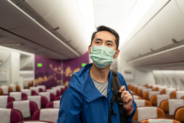 Asian traveler business man wearing mask standing on airplane.