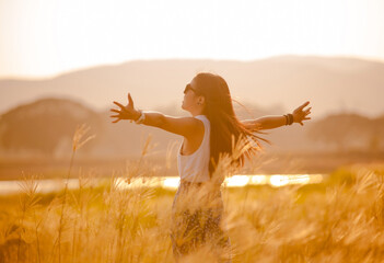 free happy woman enjoying sunset. Beautiful woman in white dress embracing the golden sunshine glow...
