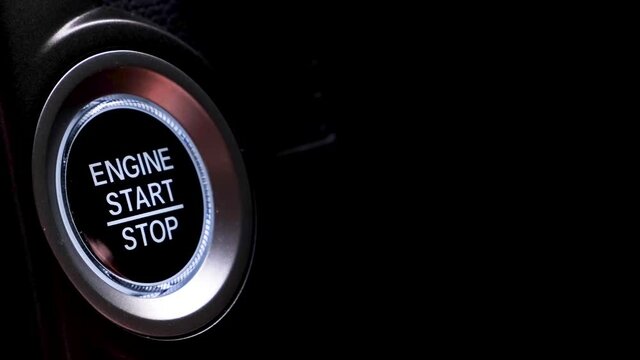 The driver's hand is pressing the car start button. Concept of transportation and technology