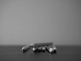 Row and stack of color pencils on table in black and white