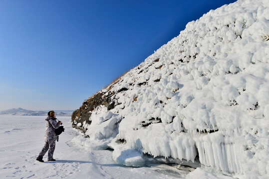 Ice on the rocks of Lake Baikal. People take pictures of beautiful ice.