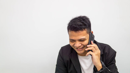 A portrait of happy young Asian businessman laughing while talking and having conversation on the phone with isolated white background. Career business job concept.