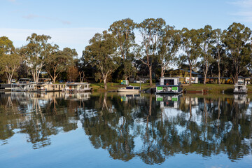 The reflection of house boats and tree on a calm river murray located in the river land at Berri South Australia on 20th June 2020