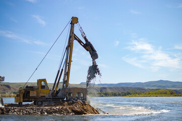 excavator digs a hole in the river