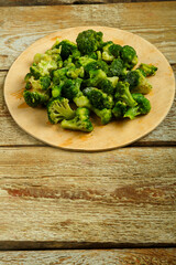 Scattered frozen broccoli on a round wooden board.