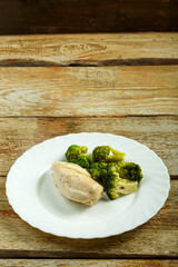 Boiled broccoli and chicken breast on a plate.