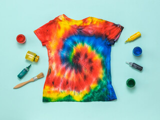 Hand-painted t-shirt in tie dye style and paint on a light blue background. Flat lay.