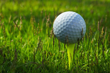 Golf ball on tee in the evening golf course with sunshine background
