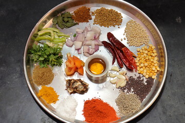 Various herbs and powder spices steel plate on black background top view