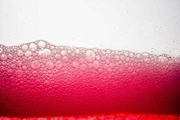Background of close-up soda bubbles mixed with red fruit juice on white background.