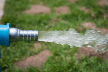 water sprinkler spraying water from blue pipe in the garden
