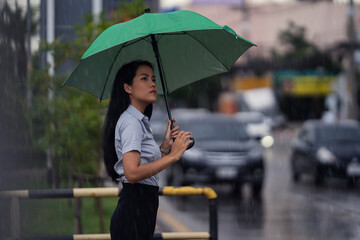 Asian woman use the umbrella while it rains She is walking across the street.