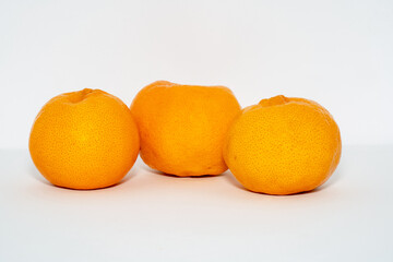 Three Orange coloured oranges/mandarins on a white background Scientific name: Citrus reticulata