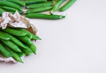 Young, fresh, juicy green peas in a paper bag on a light beige background. Place for your text....