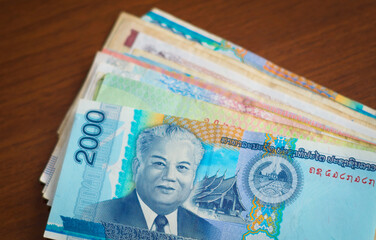 Laotian currency. Two thousand Kip bill, with the image of President Kaysone Phomvihane on it, on top of a stack of asian banknotes.
