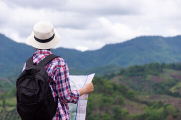Fototapeta na wymiar woman traveling with backpacker holding map looking at mountain in rain season