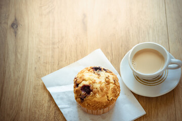 Cup of tea milk with muffin blueberry on wooden table 