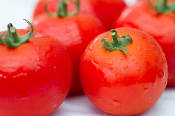 Details of a red tomato with green stipe and other blurry tomatoes in the background