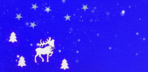 Christmas greeting card with handmade white deer in fir tree forest on blue background. Star on sky. Snow is falling. Winter Holiday concept.